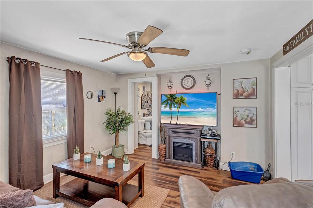 A living room features wood-look flooring, a ceiling fan, a fireplace, and a television — 2521 4TH STREET S, ST PETERSBURG, FL