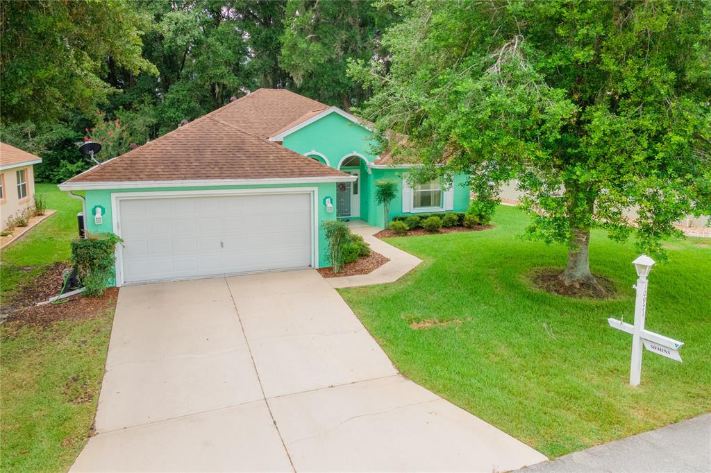 A bright green single-story house with a two-car garage and a paved driveway — 10971 SW 69TH CIRCLE, OCALA, FL