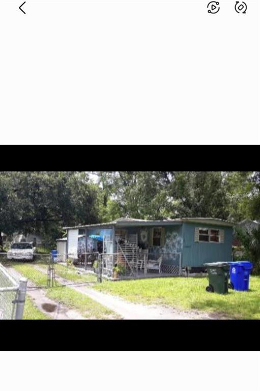 A single-story mobile home with a covered front porch and a chain-link fence — 1402 W PATTERSON STREET, LAKELAND, FL