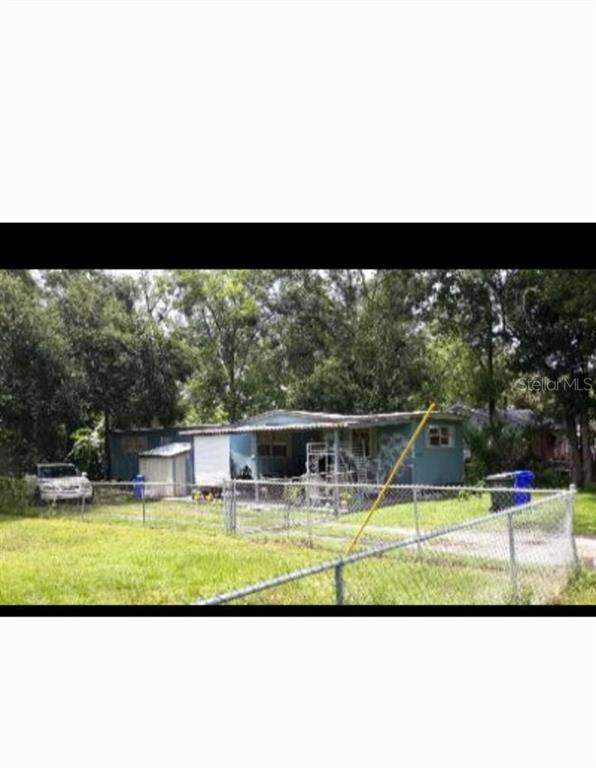 A blue mobile home with a front porch sits behind a chain-link fence — 1402 W PATTERSON STREET, LAKELAND, FL