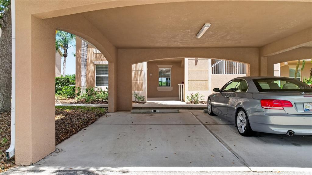 An exterior view of a multi-story building with a covered carport and parked cars — 915 FAIRWAYCOVE LANE UNIT 101, BRADENTON, FL