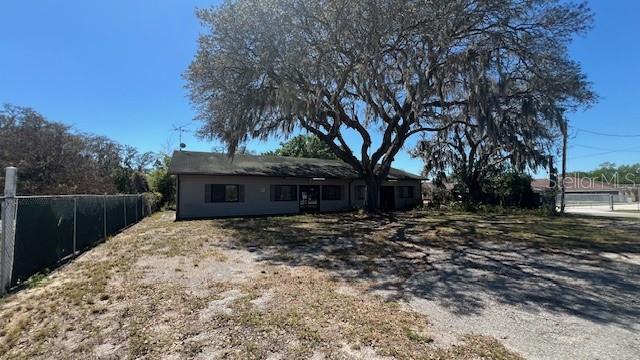 A single-story building with a large oak tree in front and a chain-link fence — 302 BROADWAY BOULEVARD SE, POLK CITY, FL