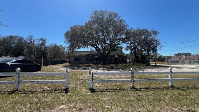 A single-story house sits behind a white rail fence under a large oak tree — 302 BROADWAY BOULEVARD SE, POLK CITY, FL