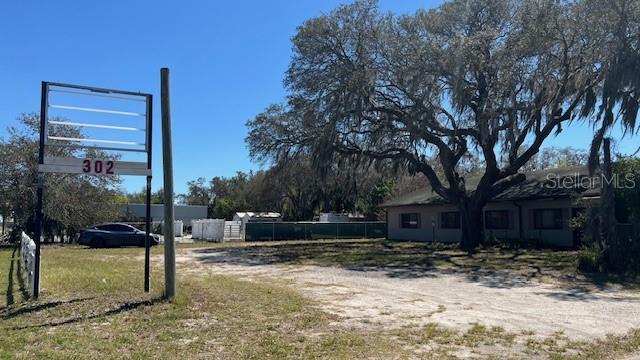 A gravel lot with a sign and a single-story building under a large oak tree — 302 BROADWAY BOULEVARD SE, POLK CITY, FL