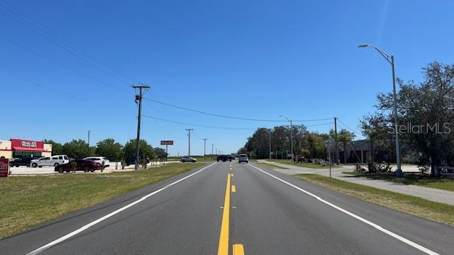 A paved road stretches toward the horizon under a clear blue sky — 302 BROADWAY BOULEVARD SE, POLK CITY, FL