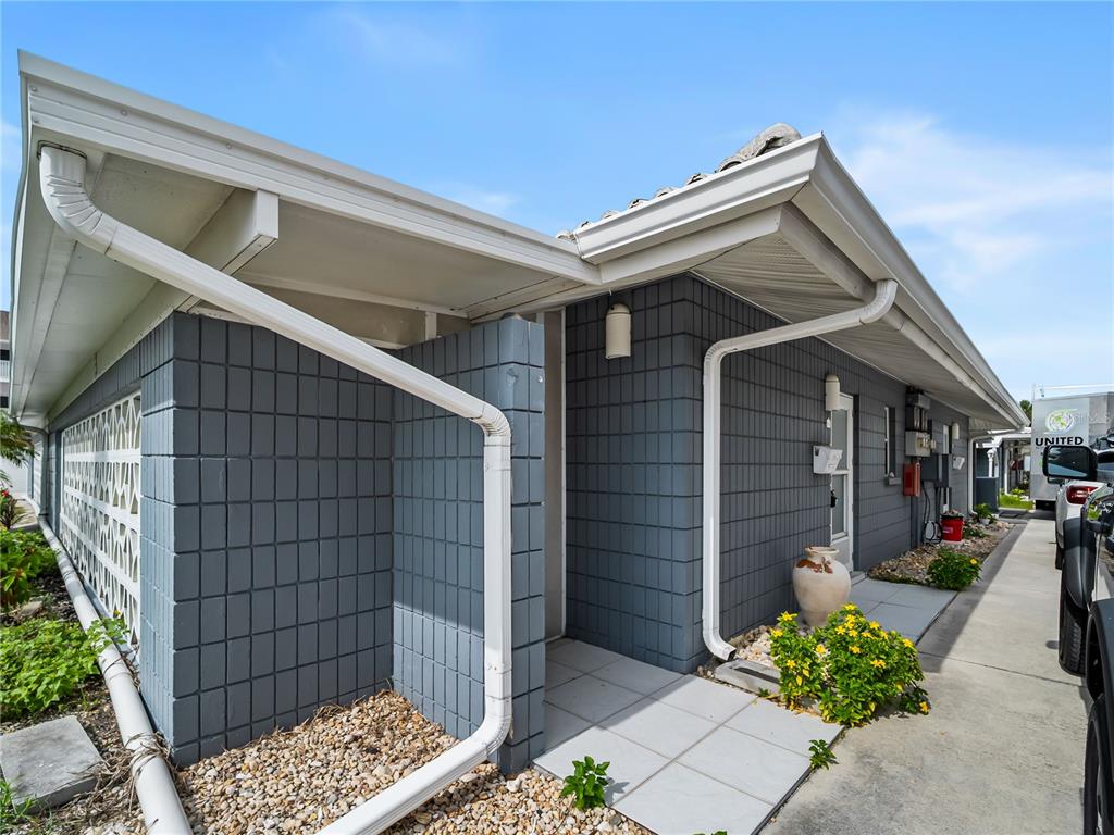 The exterior of a gray concrete block building features a covered entryway and white gutters — 1205 TARPON CENTER DRIVE UNIT C1, VENICE, FL