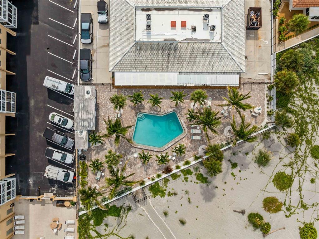 An aerial view shows a building with a swimming pool, palm trees, and parking area — 1205 TARPON CENTER DRIVE UNIT C1, VENICE, FL