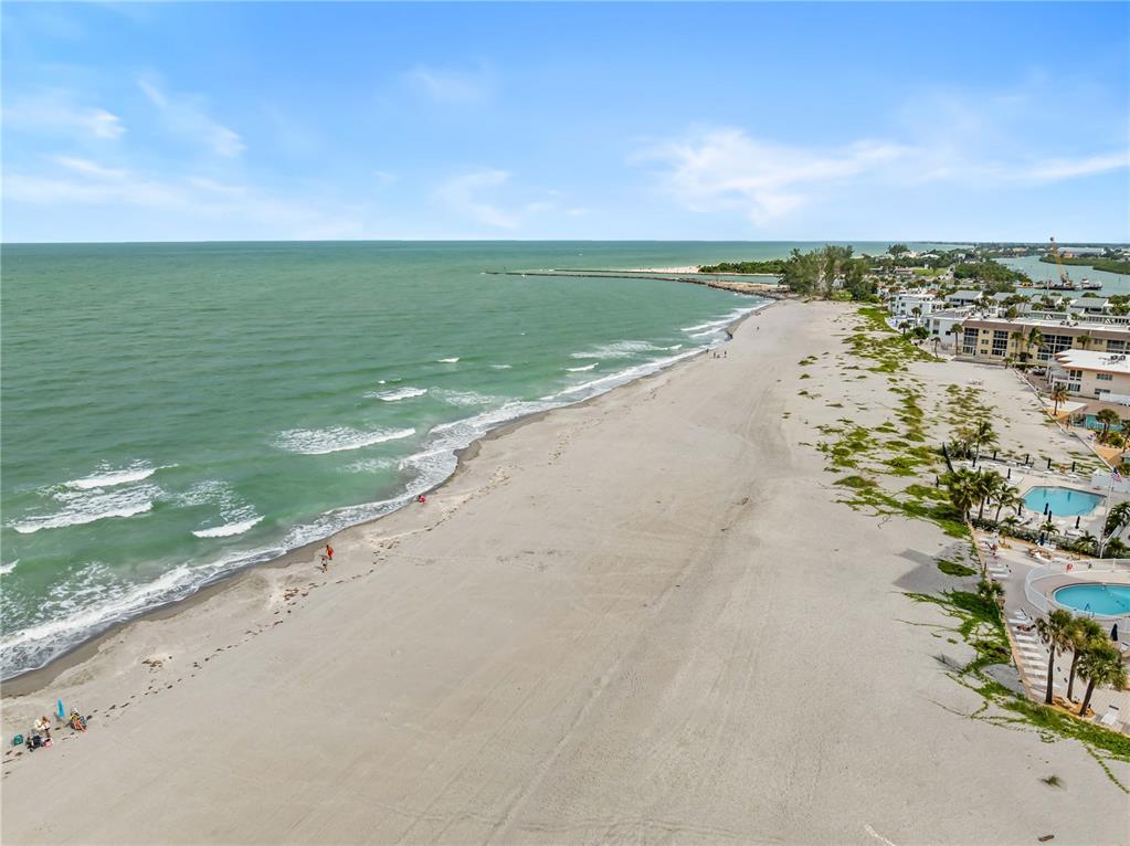 An aerial view of a sandy beach along the ocean with nearby coastal buildings and pools — 1205 TARPON CENTER DRIVE UNIT C1, VENICE, FL
