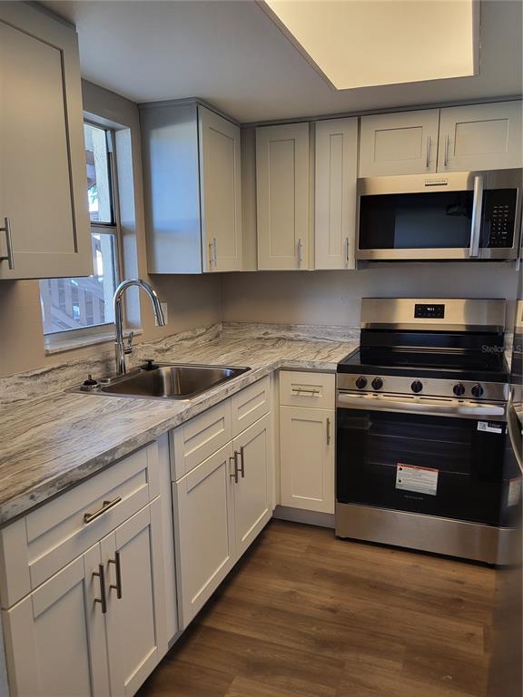 A kitchen features light gray cabinets, stainless steel appliances, and a marble-patterned countertop — 4956 HARBOR VILLA LANE UNIT 103, NEW PORT RICHEY, FL