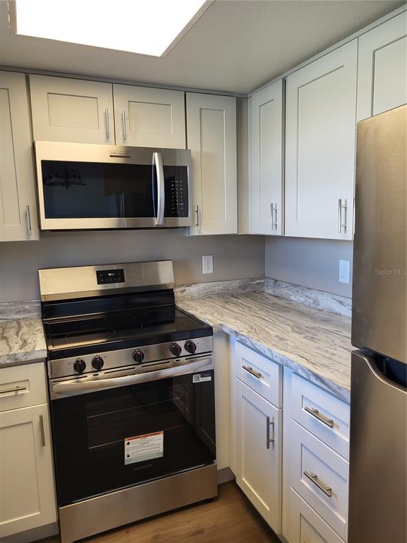 A kitchen features light gray cabinets, stainless steel appliances, and marbled countertops — 4956 HARBOR VILLA LANE UNIT 103, NEW PORT RICHEY, FL