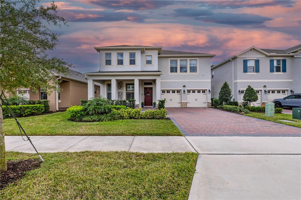 A two-story suburban house with a brick driveway, two-car garage, and a landscaped front yard — 18344 OLIVER TWIST WAY, WINTER GARDEN, FL