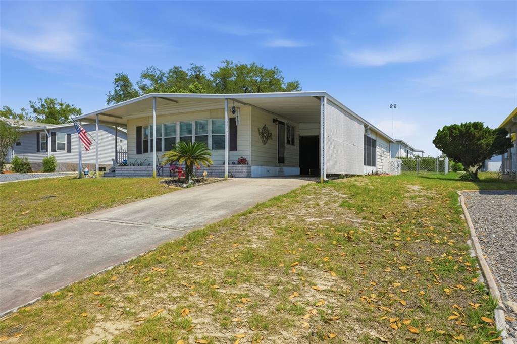 A single-story mobile home features a concrete driveway, a carport, and a small front yard — 15080 RIALTO AVENUE, BROOKSVILLE, FL