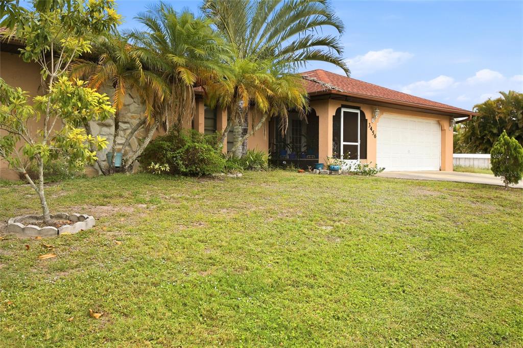 A single-story house with a tan exterior, stone accents, palm trees, and a two-car garage — 3456 DWIGHT STREET, PORT CHARLOTTE, FL