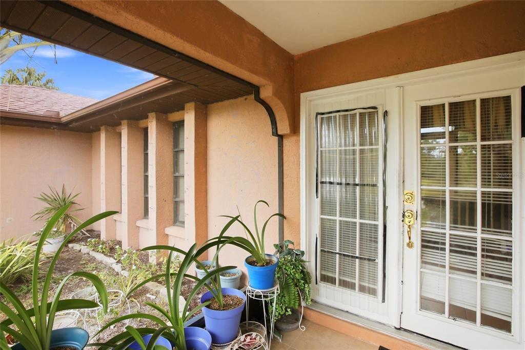 A covered patio features a stucco wall, vertical architectural columns, and white French doors — 3456 DWIGHT STREET, PORT CHARLOTTE, FL