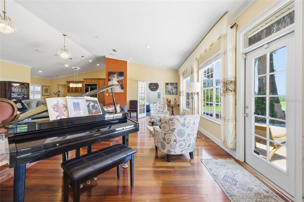 A living room features a black grand piano, hardwood floors, and a glass patio door — 1100 N PALMETTO STREET, LEESBURG, FL