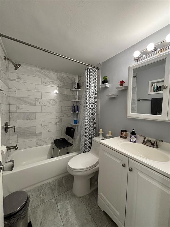 A bathroom features a marble-tiled shower, a white vanity, and a toilet — 5820 N CHURCH AVENUE UNIT 348, TAMPA, FL