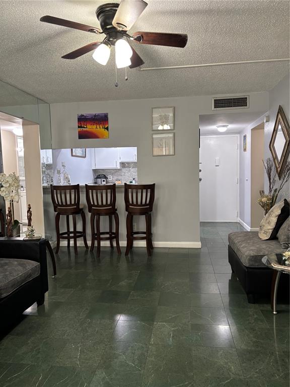 A living room with green tile flooring, a ceiling fan, and a kitchen breakfast bar — 5820 N CHURCH AVENUE UNIT 348, TAMPA, FL