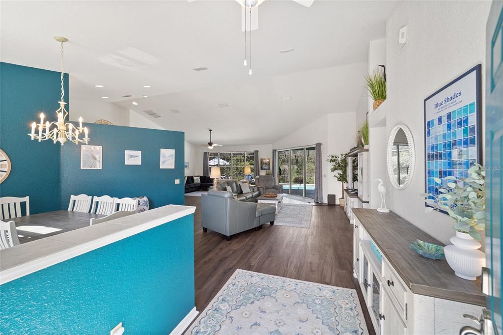 An open-concept living and dining area features teal accent walls, wood-look flooring, and sliding doors — 9781 SW 196TH CIRCLE, DUNNELLON, FL