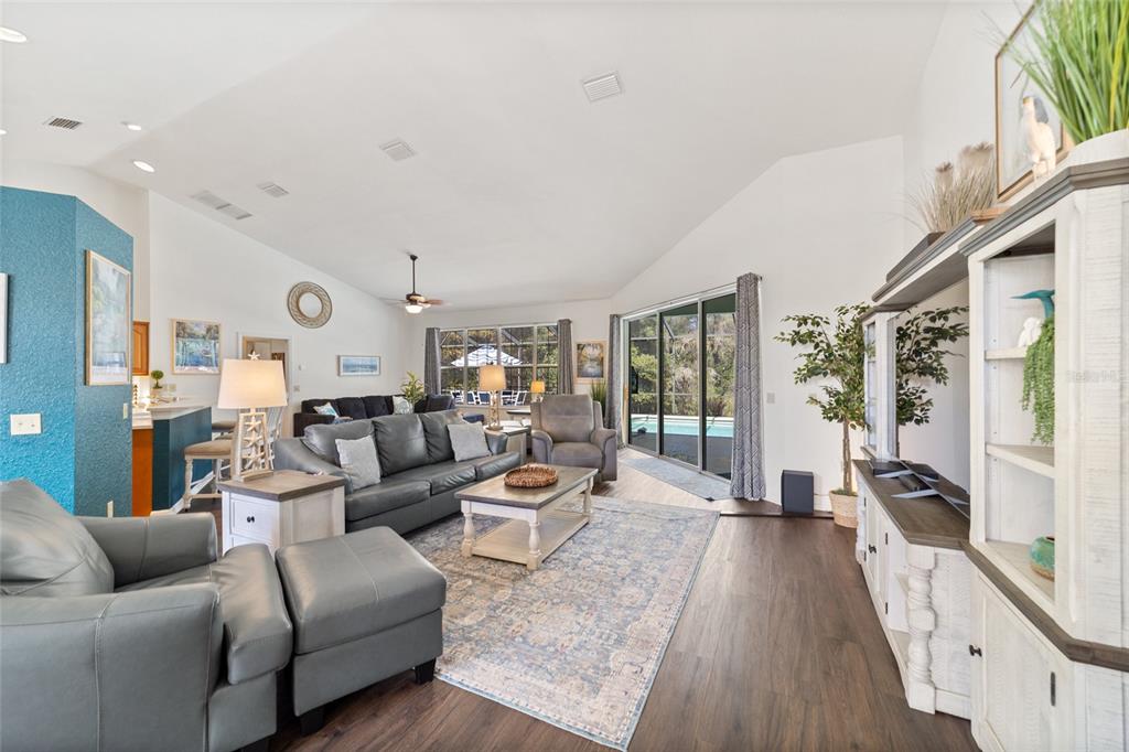 A living room features gray leather furniture, a patterned area rug, and sliding glass doors — 9781 SW 196TH CIRCLE, DUNNELLON, FL