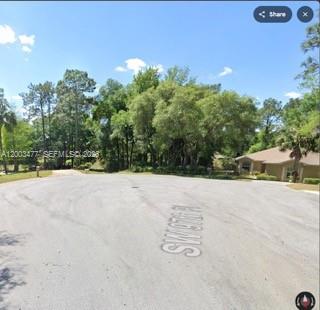A paved cul-de-sac street leads toward a wooded area and a residential house — 0 SW SW 97 PL, Dunnellon, Ocala FL 34432, OCALA, FL