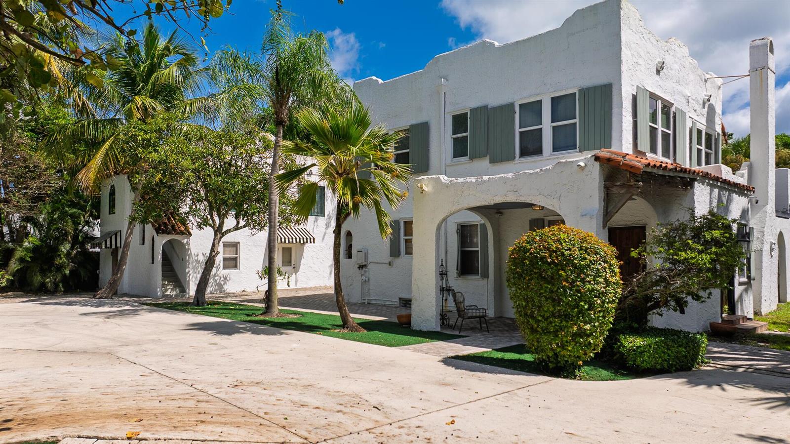 A white stucco two-story building features arched entryways, green shutters, and palm trees — 717 Forest Hill Boulevard, West Palm Beach FL 33405, WEST PALM BEACH, FL