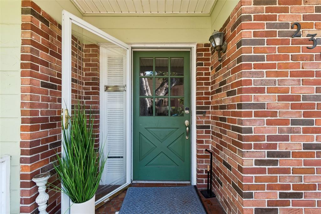 A green front door with a glass pane sits between two brick walls — 2302 S ARRAWANA AVENUE, TAMPA, FL