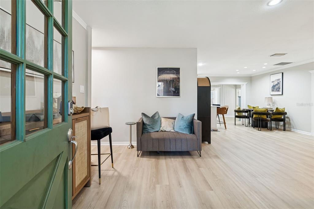 A view from an open green door into a living area with light wood flooring — 2302 S ARRAWANA AVENUE, TAMPA, FL