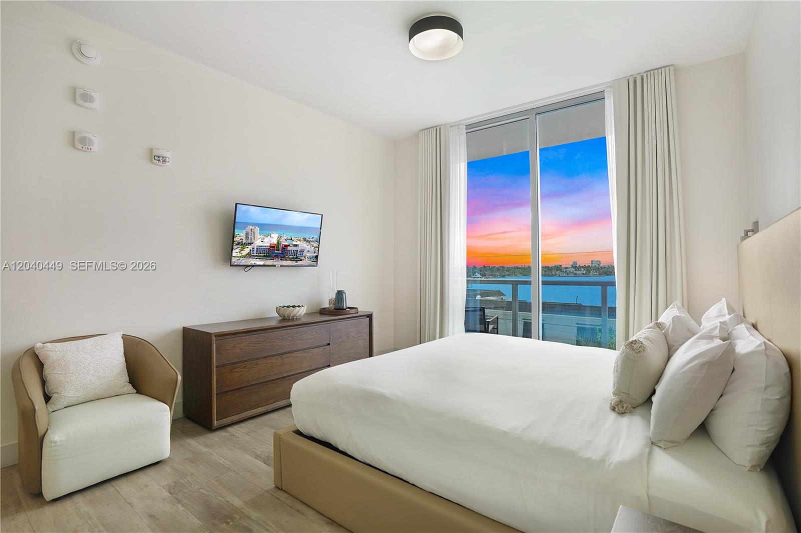 A bedroom features a bed, a dresser with a television, and a balcony with water views — 777 N Ocean Dr # S332, Hollywood FL 33019, HOLLYWOOD, FL