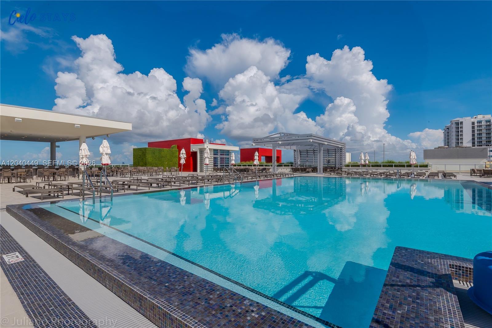 A rooftop swimming pool with lounge chairs and umbrellas under a bright blue sky — 777 N Ocean Dr # S332, Hollywood FL 33019, HOLLYWOOD, FL