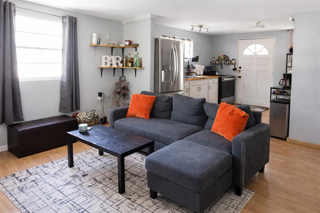 A living room with a gray sectional sofa, coffee table, and open kitchen area — 2211 SE 51ST STREET, GAINESVILLE, FL