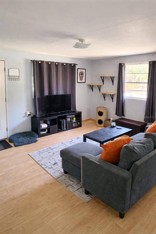 A living room features a gray sectional sofa, a television stand, and wall-mounted cat shelves — 2211 SE 51ST STREET, GAINESVILLE, FL