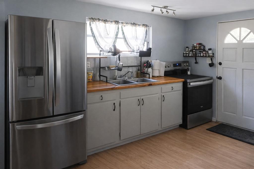 A kitchen features stainless steel appliances, gray cabinets, a wood countertop, and a sink — 2211 SE 51ST STREET, GAINESVILLE, FL