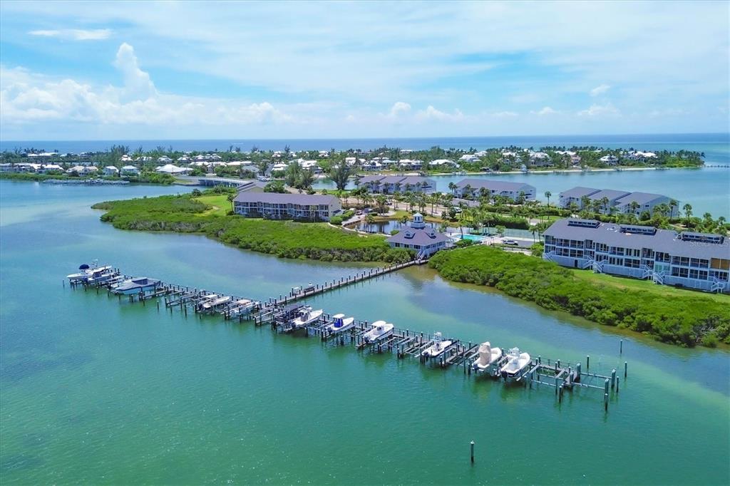 An aerial view shows a long boat dock extending into a bay near waterfront condominiums — 6001 BOCA GRANDE CAUSEWAY UNIT E58, BOCA GRANDE, FL