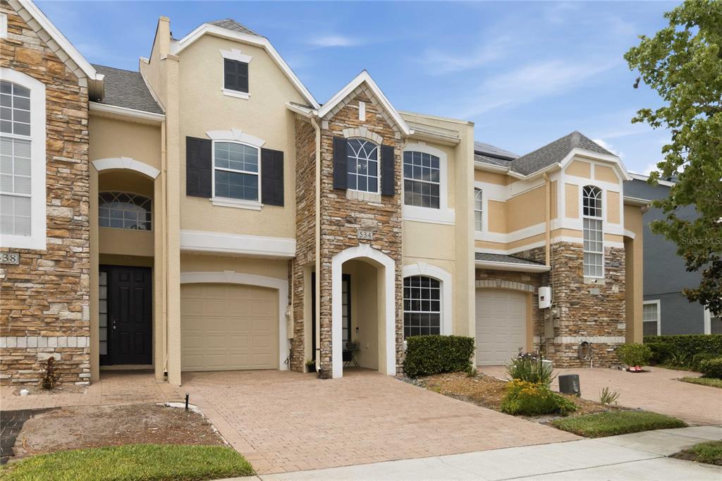A two-story townhouse with a stone facade, beige stucco, and two attached garages — 534 TERRACE SPRING DRIVE, ORLANDO, FL