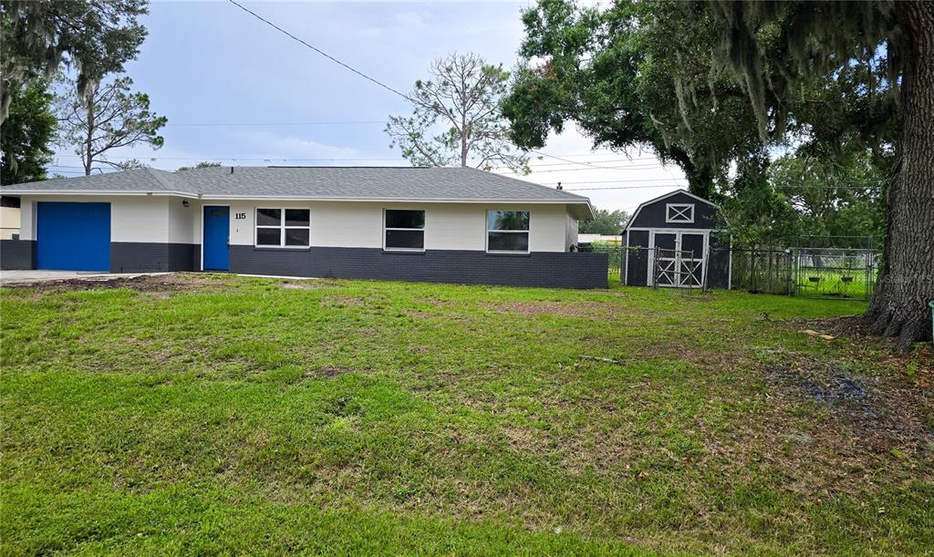 A single-story house with a blue garage door and front door, plus a storage shed — 115 PADGETT PLACE S, LAKELAND, FL
