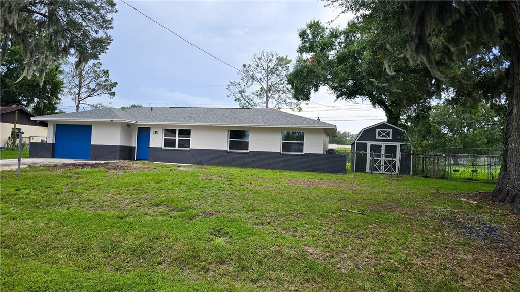 A single-story house with a two-tone exterior, a blue garage door, and a detached shed — 115 PADGETT PLACE S, LAKELAND, FL