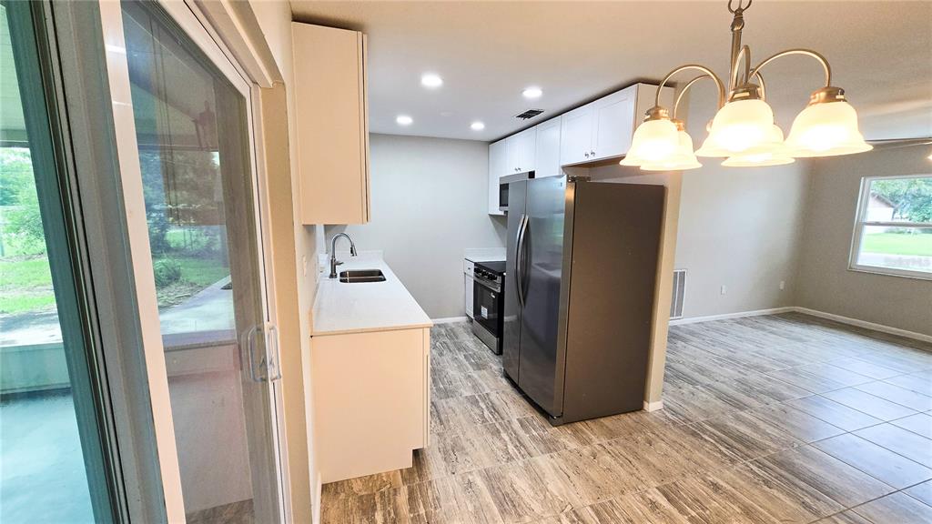 A kitchen features white cabinets, stainless steel appliances, and wood-look tile flooring — 115 PADGETT PLACE S, LAKELAND, FL