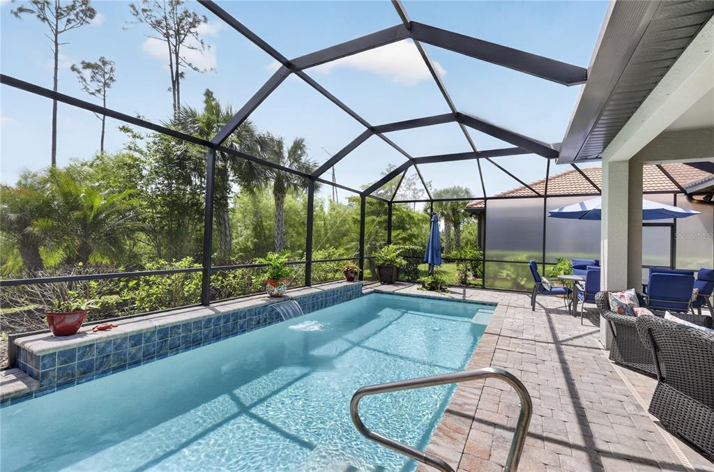 A screened-in patio features a rectangular swimming pool with a small water feature and pavers — 2633 DAISY DRIVE, NORTH PORT, FL