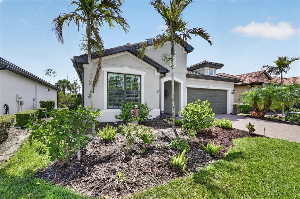 A single-story house with a gray stucco exterior, a two-car garage, and palm trees — 2633 DAISY DRIVE, NORTH PORT, FL