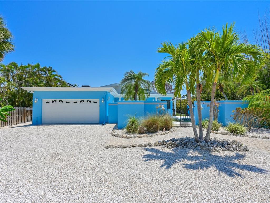 A bright blue house with a white garage door and palm trees on a gravel lot — 5920 GULF OF MEXICO DRIVE, LONGBOAT KEY, FL