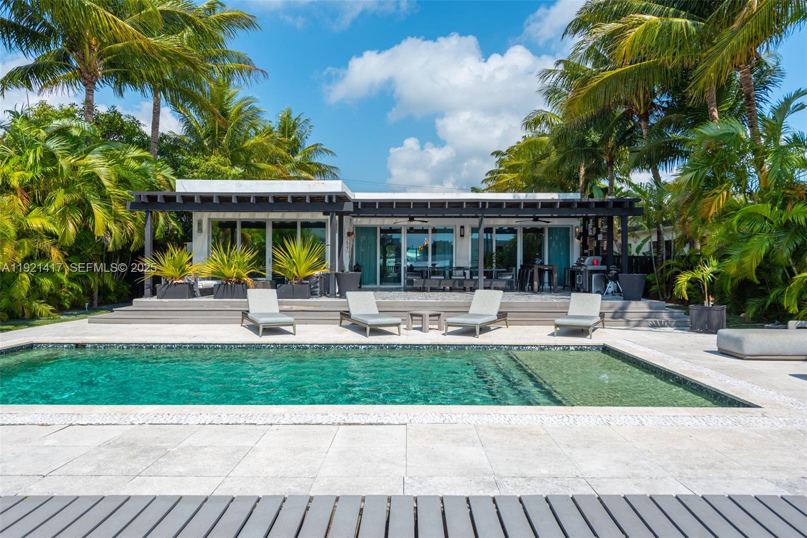 A modern house exterior features a swimming pool, lounge chairs, and a covered patio area — 970 S Shore Dr, Miami Beach FL 33141, MIAMI BEACH, FL