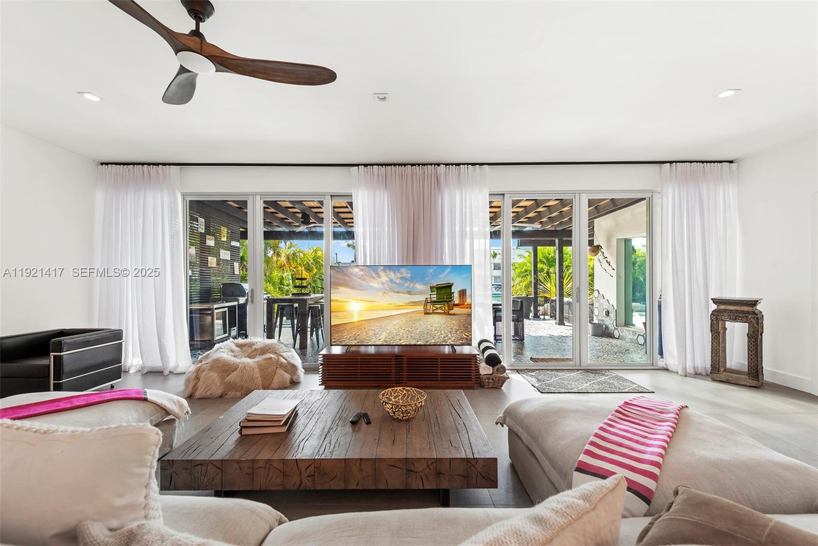 A living room features a wooden coffee table, a television, and sliding glass patio doors — 970 S Shore Dr, Miami Beach FL 33141, MIAMI BEACH, FL
