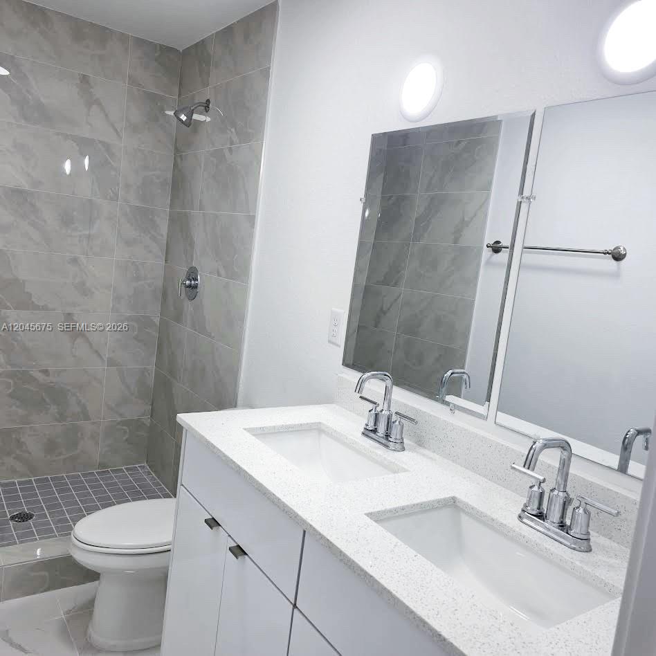 A modern bathroom features a double vanity with white cabinets, quartz countertops, and a tiled shower — 2731 NW 44th St # 2731, Miami FL 33142, MIAMI, FL