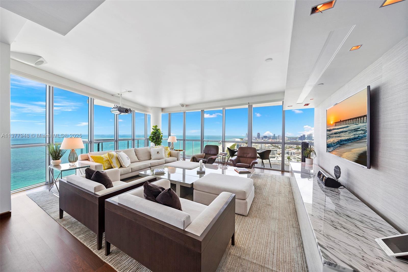 A modern living room features floor-to-ceiling windows with ocean views and a marble media console — 101 20th St # 3909, Miami Beach FL 33139, MIAMI BEACH, FL
