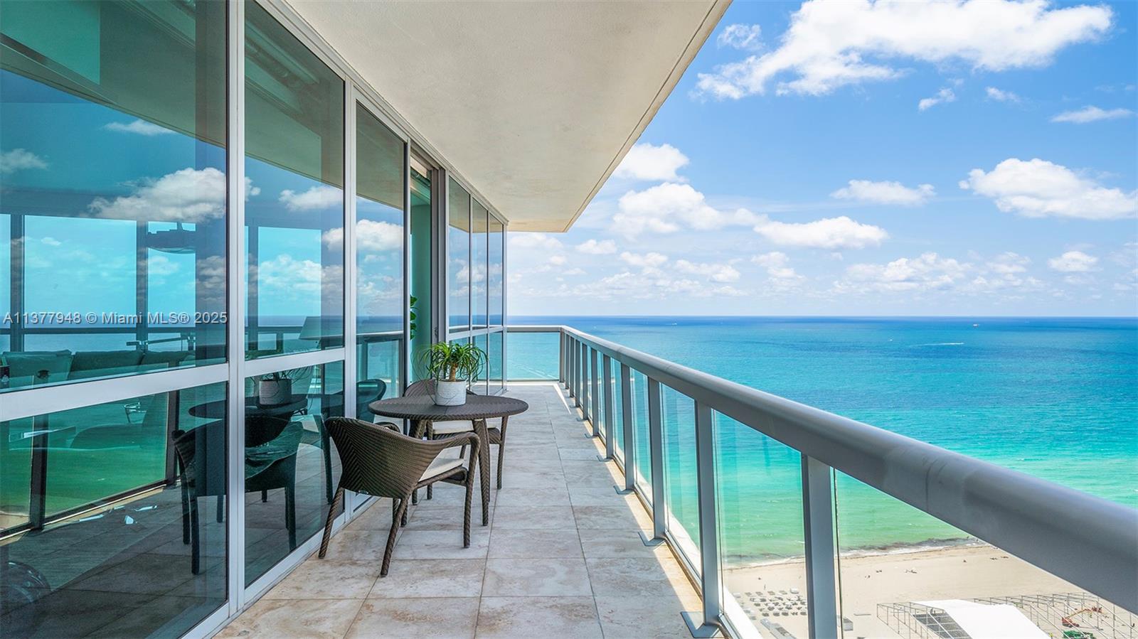 A balcony with a glass railing overlooks the ocean and a sandy beach below — 101 20th St # 3909, Miami Beach FL 33139, MIAMI BEACH, FL