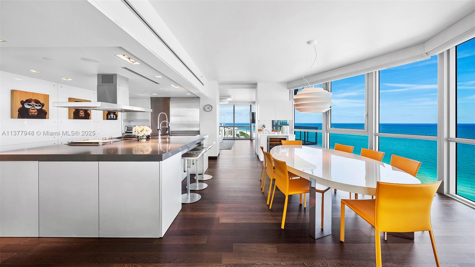 A modern kitchen and dining area feature white cabinetry, dark wood floors, and ocean views — 101 20th St # 3909, Miami Beach FL 33139, MIAMI BEACH, FL