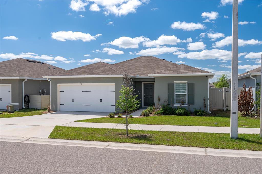 A single-story house with a gray exterior, white garage door, and a brown shingled roof — 166 PIAVE STREET, HAINES CITY, FL