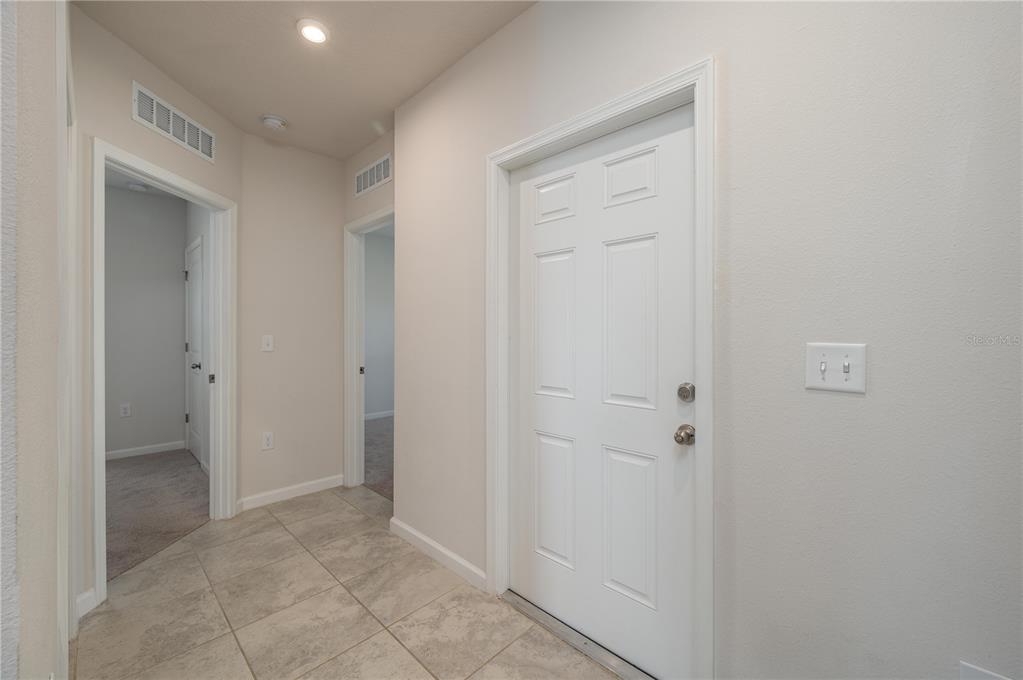 A tiled entryway features a white door, light-colored walls, and two doorways leading to carpeted rooms — 166 PIAVE STREET, HAINES CITY, FL