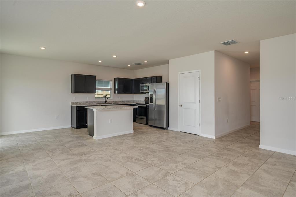 An open-concept kitchen features dark cabinetry, stainless steel appliances, and a central island — 166 PIAVE STREET, HAINES CITY, FL