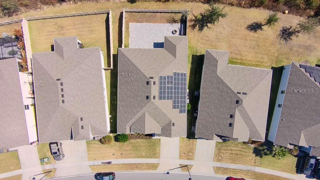An aerial view shows three suburban houses with shingled roofs, driveways, and fenced backyards — 3647 VEGA CREEK DRIVE, ST CLOUD, FL